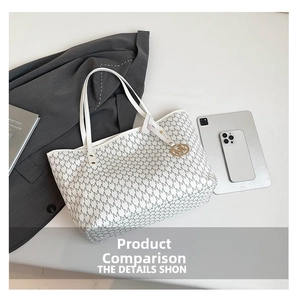 Detail view of white monogram tote bag with gold M charm on grey office background