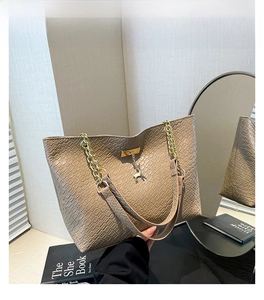 Detail of khaki tote bag with diamond quilted texture and elegant gold chain strap