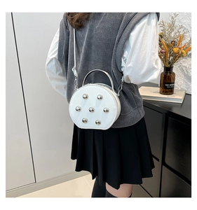 White circular rivet crossbody bag shown on model with matte leather and silver hardware