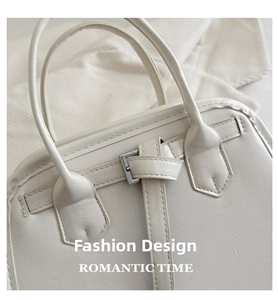 Detail of off-white leather tote bag featuring a textured finish and silver metal buckle