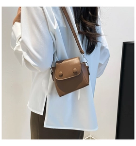 Brown leather mini crossbody bag shown on model highlighting compact size and chic style