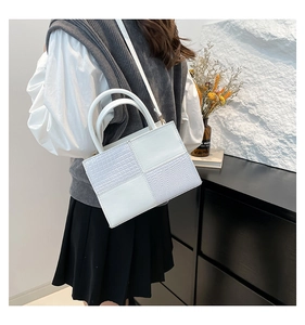 Détail d'un sac à main blanc à texture crocodile porté par un mannequin en vue arrière