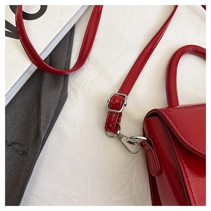 Close-up of vibrant red patent leather bag with glossy finish and silver hardware