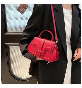 Dettaglio della borsa rossa in pelle con fibbia in metallo dorato e trama grana