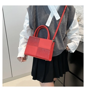 Détail du sac à bandoulière rouge carré avec texture patchwork porté par un mannequin