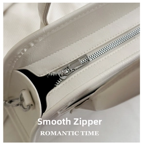 Detailed close-up of smooth silver metal zipper on premium white leather tote bag
