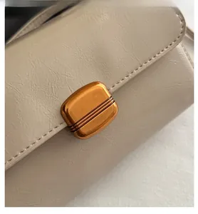 Macro shot of beige leather pleat texture and gold metal buckle on a shoulder bag