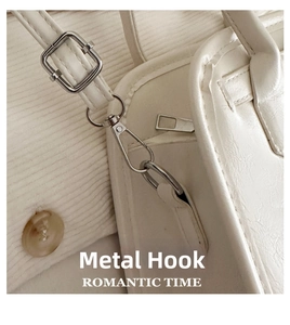 Macro shot of silver metal hardware hook and adjustable shoulder strap on white handbag