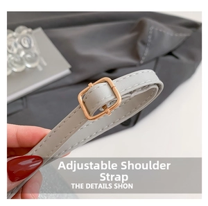 Détail macro d'une bandoulière en cuir gris clair réglable avec boucle dorée