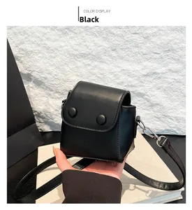 Detailed view of black mini crossbody bag featuring flap closure and two round decorative buckles