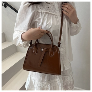 Détail d'un sac à main vintage en cuir PU marron avec boucle sur fond de robe blanche