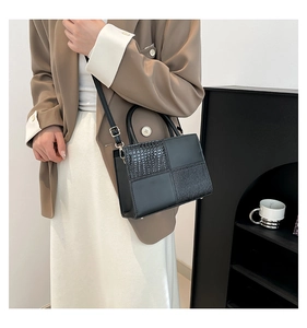 Détail du sac à main noir avec patchwork motif crocodile et fermoir métallique élégant