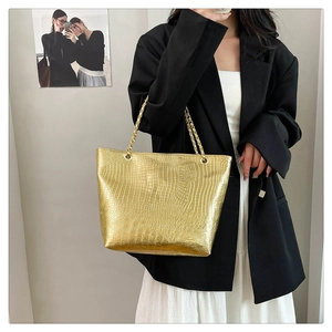 Close-up of golden crocodile pattern tote bag with stylish dual chain handles