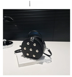 Detail of black round leather bag with silver studs and metal zipper closure