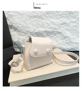 Detail view of mini white crossbody bag with round decorative buckles and detachable strap