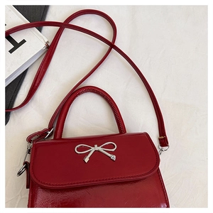 Close-up of red PU square bag with silver metal bow buckle and glossy oil-wax finish