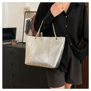 Sac cabas argenté motif crocodile avec bandoulière chaîne porté par un mannequin en intérieur