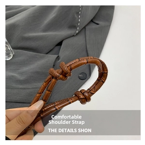 Detail of the brown glossy knotted shoulder strap with bamboo texture on a lady handbag