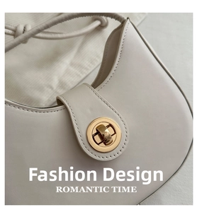 Close-up of cream leather crescent bag with elegant gold circular swivel lock clasp