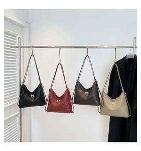 Detail of four textured tote bags in black, burgundy, coffee, and gold with silver bows