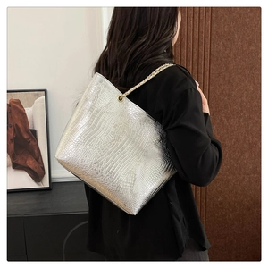 Détail du sac cabas argenté avec motif crocodile et bandoulière en chaîne dorée