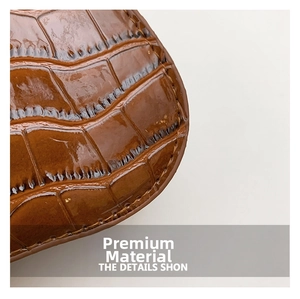 Close-up of shiny dark brown crocodile embossed faux leather texture on luxury handbag