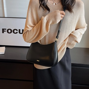 Minimalist black leather baguette bag for women shown as an underarm shoulder bag