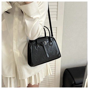 Detail of black wrinkled texture handbag with silver buckles and elegant shoulder strap