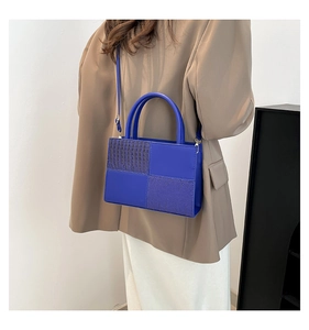 Détail du sac à main bleu en cuir croco porté en bandoulière sur un mannequin