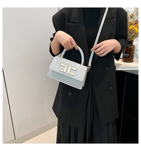 Gros plan du sac à main à paillettes avec fermoir doré porté par un mannequin en costume
