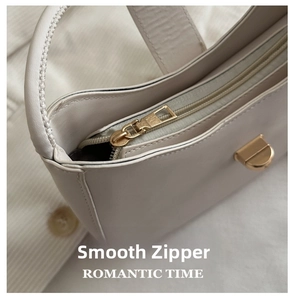 Close-up of smooth light beige leather handbag featuring a premium gold metal zipper detail
