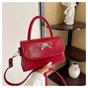 Detail shot of the glossy red patent leather surface with a silver bow buckle