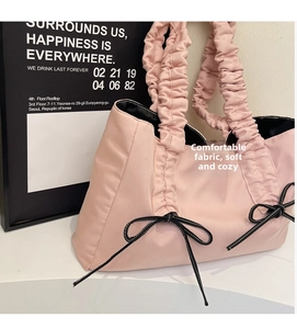 Detail of pink nylon tote bag featuring pleated handles and decorative black bows