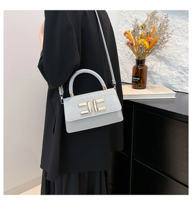 Détail du sac carré bleu-gris avec texture pailletée et boucle en métal doré