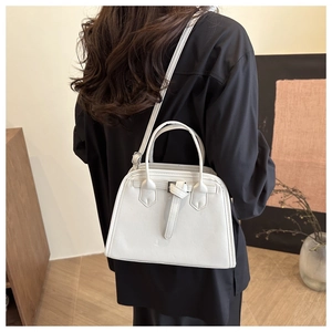 Modern white leather handbag shown on shoulder in a minimalist home setting