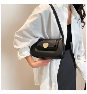 Detail showing smooth matte black leather shoulder bag with a large gold heart metal buckle