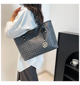 Détail d'un sac porté épaule vintage avec monogramme et pendentif doré sur le mannequin