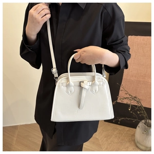 Close-up of white minimalist crossbody bag with decorative buckle and thin shoulder strap
