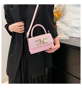 Détail du sac rose pailleté avec boucle dorée sur un mannequin en blazer noir