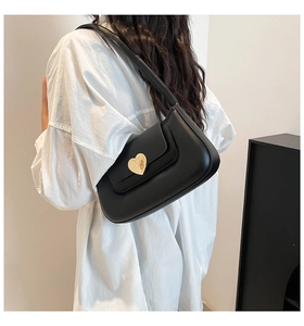 Detail of a black French shoulder bag featuring a large gold heart-shaped metal buckle