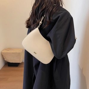 Minimalist cream white leather hobo bag worn by model in a stylish indoor setting