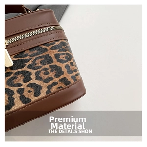 Detailed macro view of leopard print canvas with premium leather trim and golden zippers