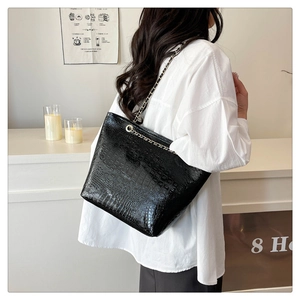 Détail du cabas en cuir verni noir à motif crocodile avec bandoulière chaîne
