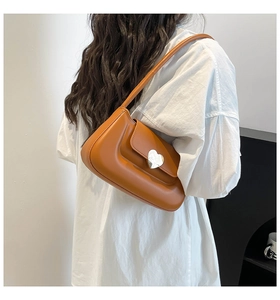 Caramel brown shoulder bag with silver heart lock detail shown on a model's shoulder