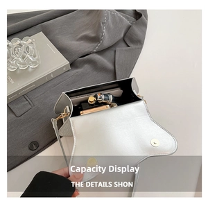 Detail view of silver crossbody bag interior showing storage capacity for phone and perfume