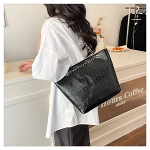 Détail du sac cabas noir à motif crocodile avec une élégante bandoulière chaîne dorée