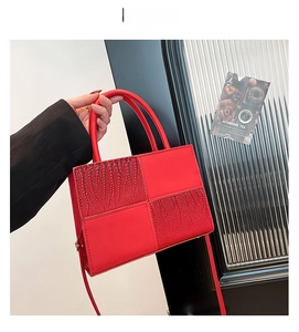 Détail du sac à main rouge avec textures crocodile mixtes et poignées cylindriques