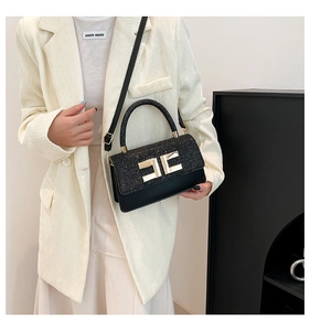 Détail du sac à main en tweed noir et cuir avec fermoir doré et poignée arrondie