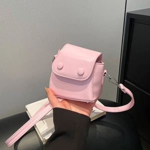 Mini pink leather crossbody bag with decorative round buckles and adjustable shoulder strap