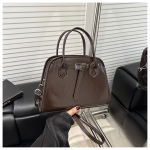 Close-up of a dark brown glossy handbag with elegant buckle detail and dual handles